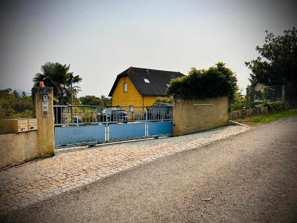 a house with a blue fence and a yellow house at Maison Fleurie in Aubertin