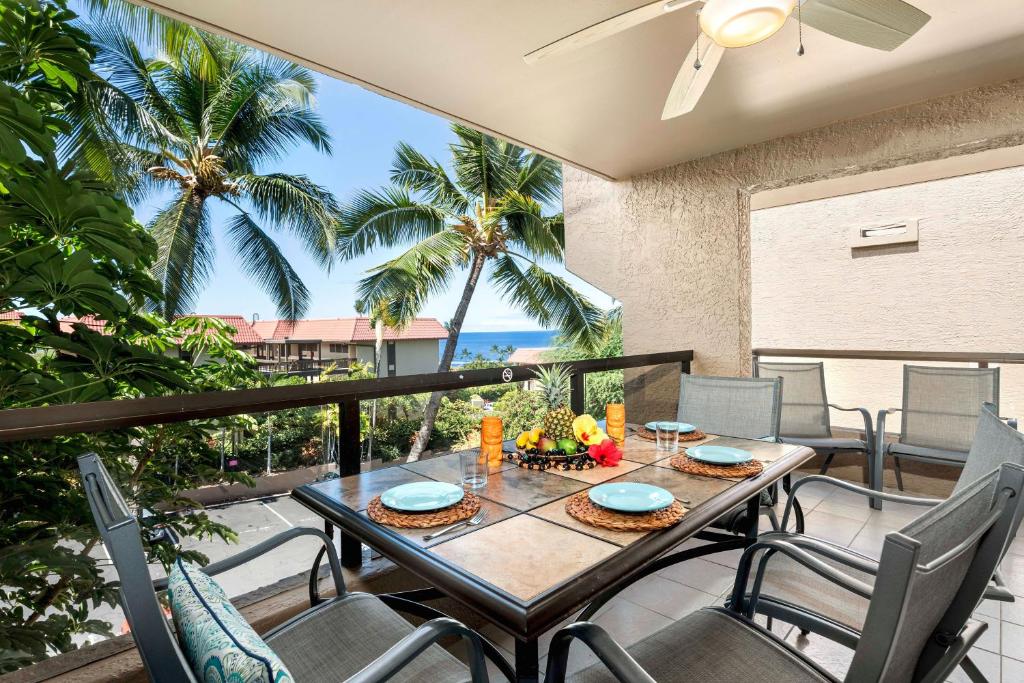 a table and chairs on a balcony with palm trees at Kona Pacific D622 in Kailua-Kona