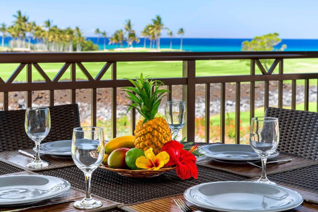 a table with a basket of fruit and wine glasses at Halii Kai 11D in Waikoloa