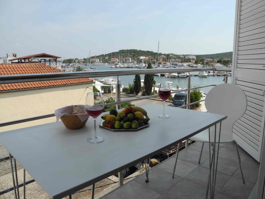 a table with a bowl of fruit and two glasses of wine at Apartments JP in Jezera