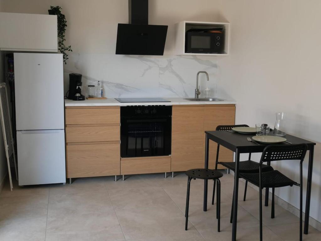a kitchen with a black table and a white refrigerator at Studios Saint Mau 4 in Saint-Maurice-de-Gourdans
