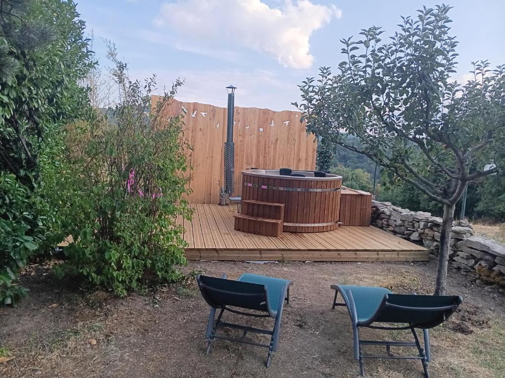 a wooden deck with two chairs and a hot tub at studio indépendant dans maison à la campagne in Égliseneuve-près-Billom