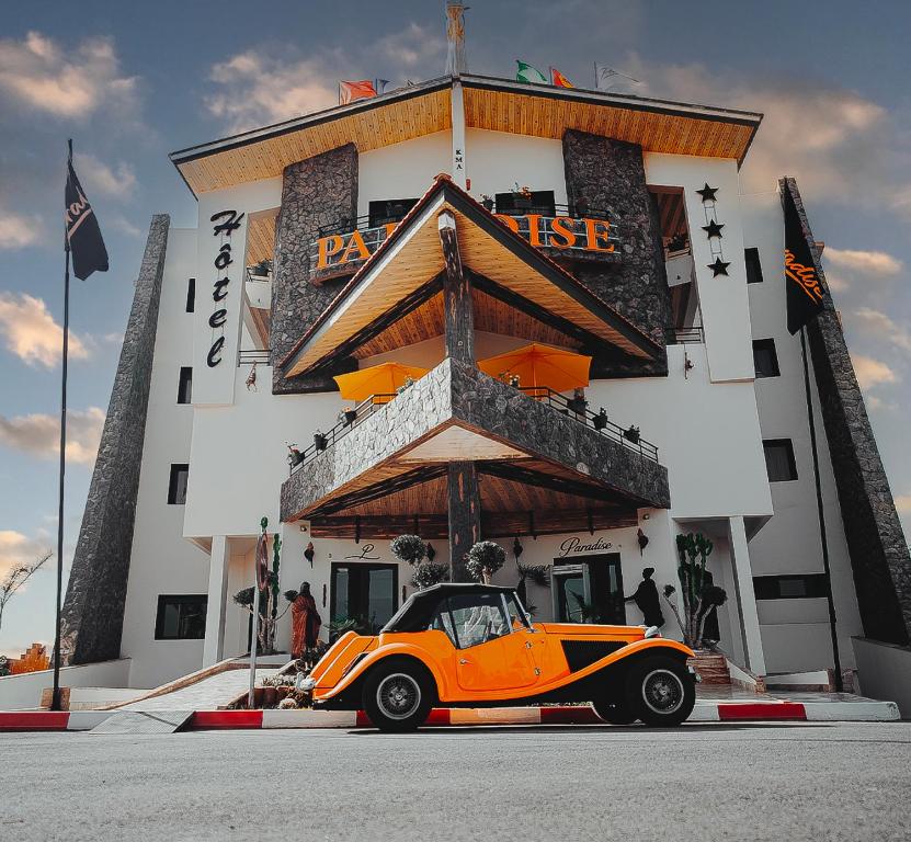 an orange car parked in front of a building at Hotel Paradise KMA in Bouznika