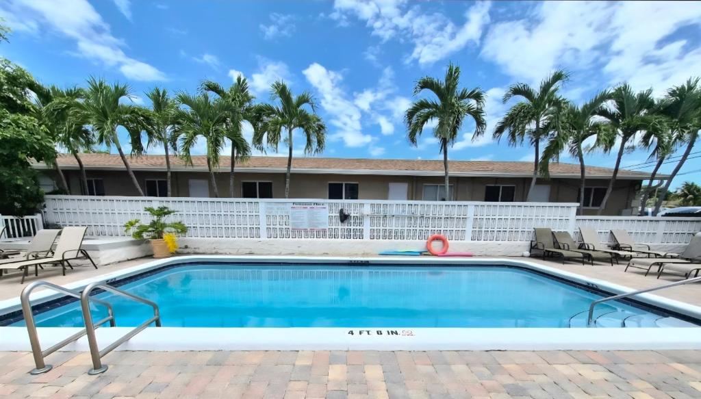 a swimming pool in front of a resort with palm trees at Charming Condo - Pool, Minutes to Beach in Pompano Beach