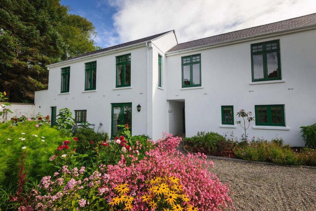 a white house with flowers in front of it at Milntown Self Catering Apartments in Ramsey