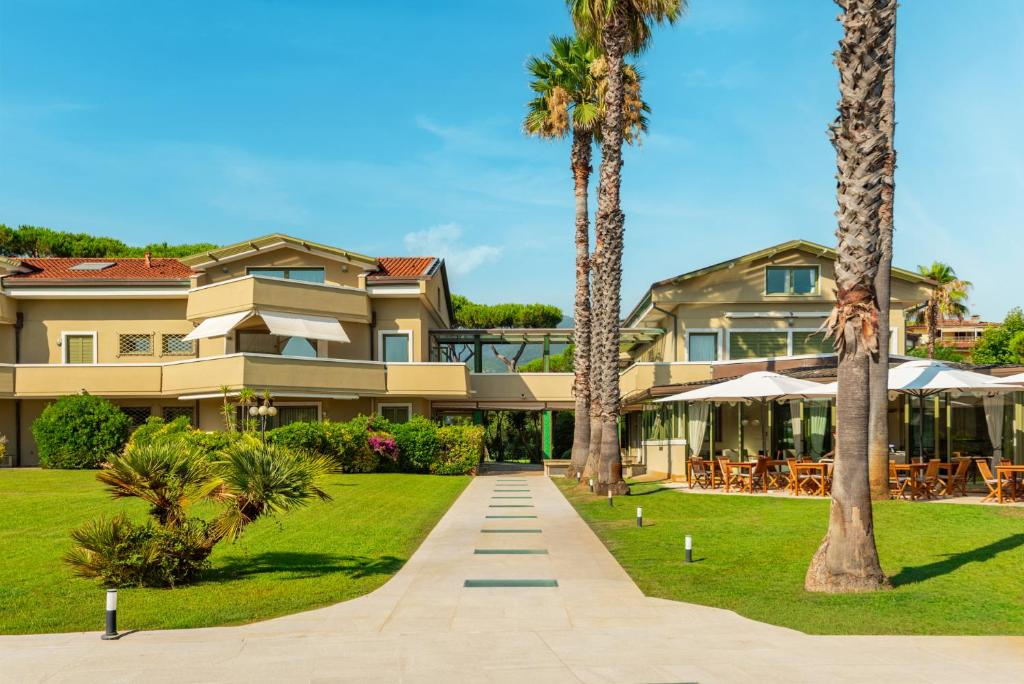 a house with palm trees and a walkway at Hotel Villa Undulna - Terme della Versilia in Cinquale