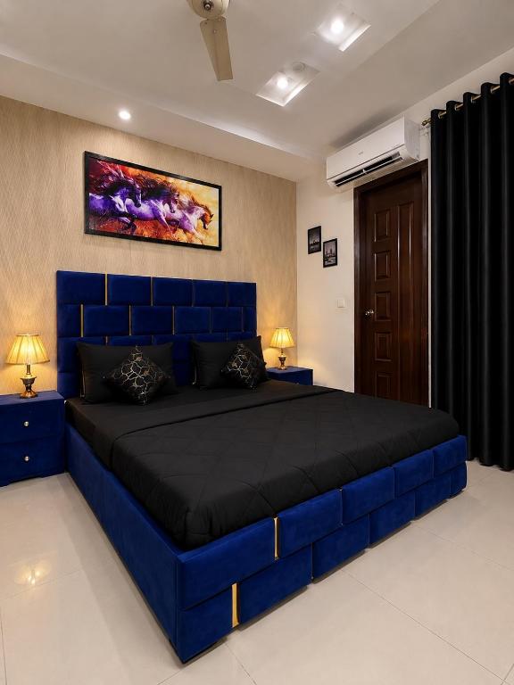 a large blue bed in a room with two lamps at Family-Friendly Luxury Apartment Home Away From Home in Islamabad