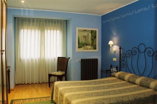 a blue bedroom with a bed and a chair at Hotel Conventin in Villaviciosa