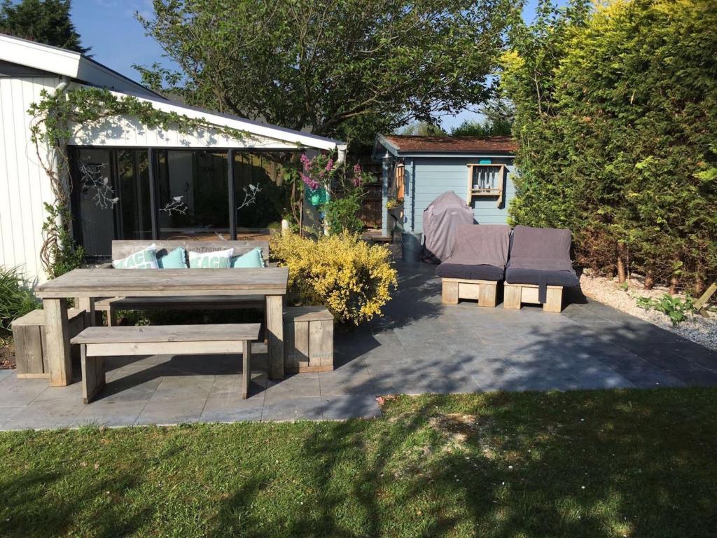 a patio with a picnic table and a bench at Place2BEach-Bungalow in Noordwijk aan Zee