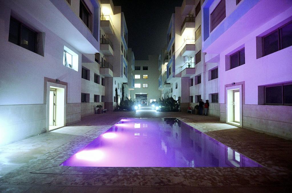 a pool in the middle of a building at night at sunny amazigh apt avev piscine pool steps from beach 2balcony 2smartTV pool in Essaouira