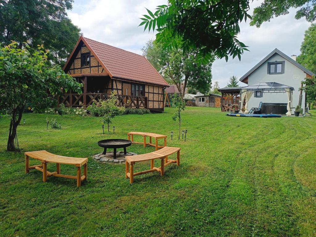 a group of benches in the grass in front of a house at Jesionowy Zakątek domki z balią blisko jeziora in Piasutno