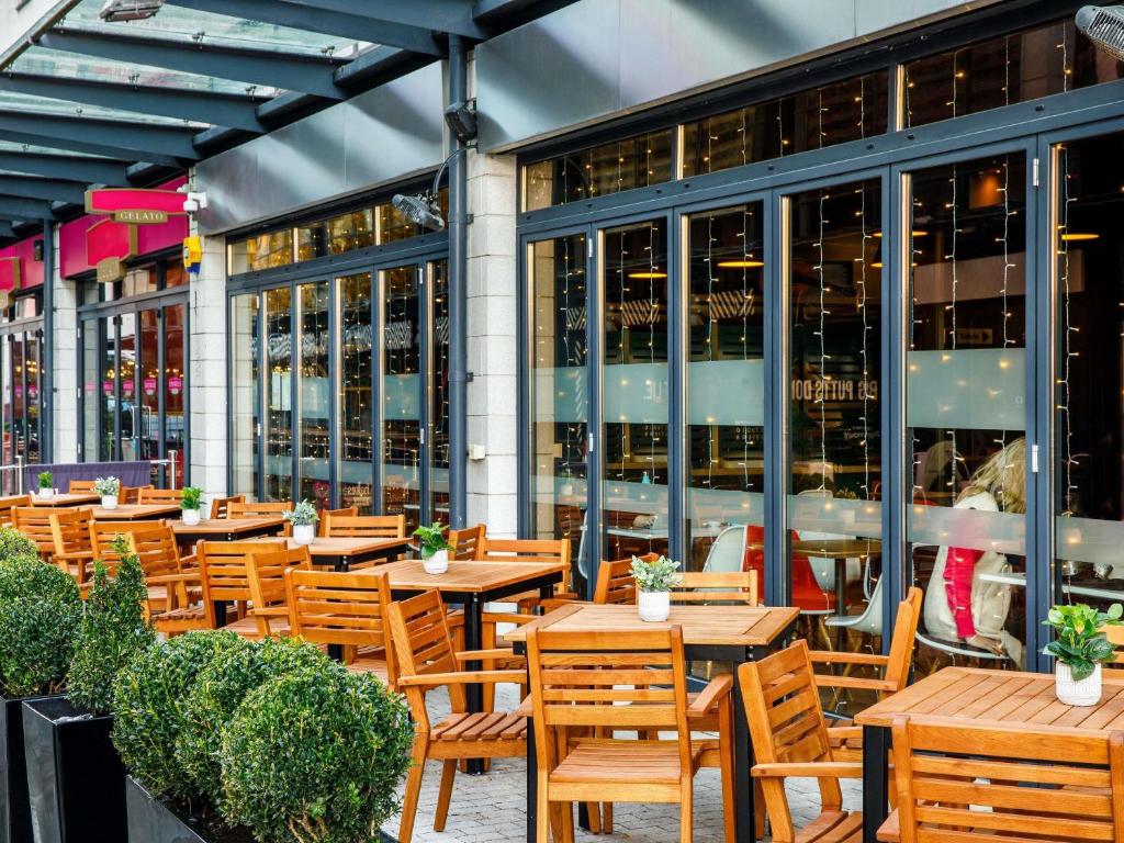 a restaurant with wooden tables and chairs in front of a building at ibis Bristol Centre in Bristol