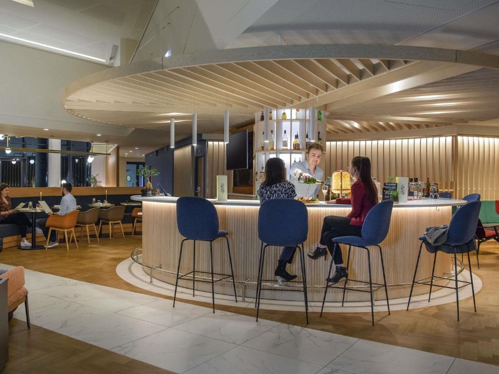a group of people sitting at a bar in a restaurant at Novotel Le Havre Centre Gare in Le Havre