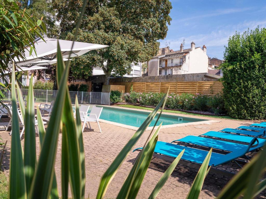 a row of blue lounge chairs next to a swimming pool at ibis Styles Macon Centre in Mâcon
