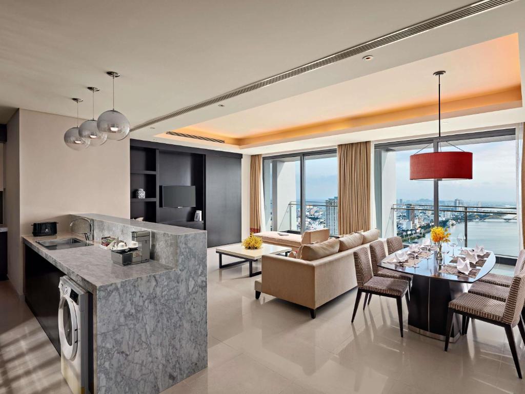 A large apartment living space with a marble kitchen island, dining area and water view.
