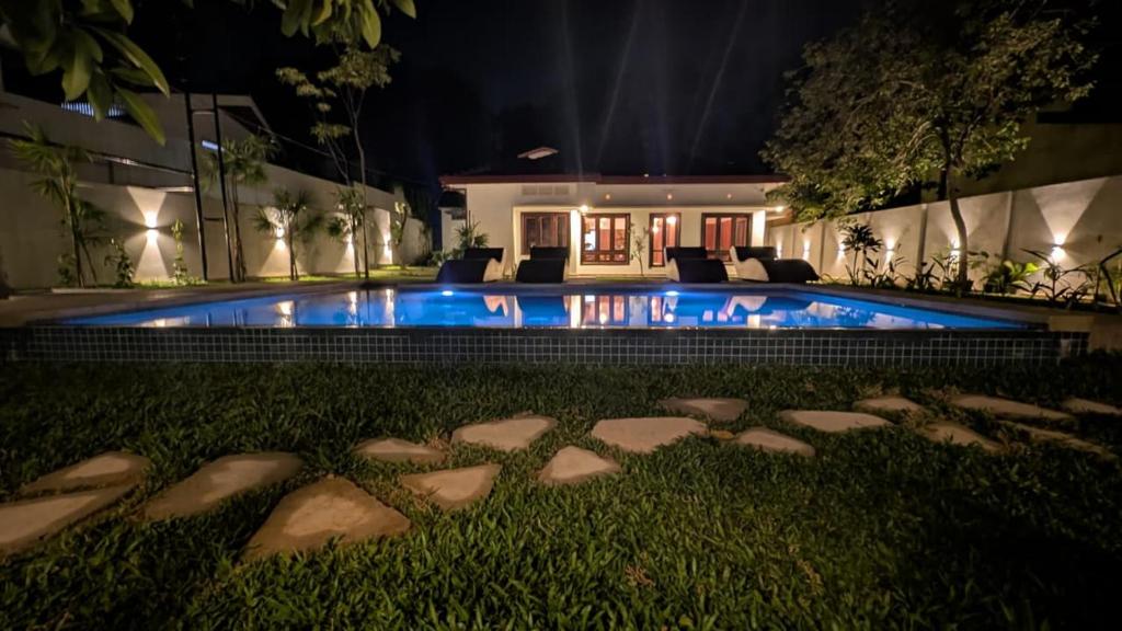 a swimming pool in front of a house at night at The Ocean Breeze Villa in Tangalle