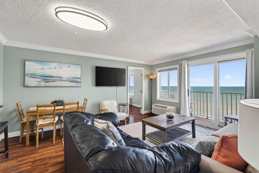 a living room with a couch and a table at Oceanfront Beach Condo, Pool, Gym, Fishing Surfing in Virginia Beach