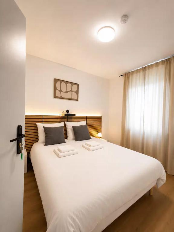 a large white bed in a room with a window at Hotel de la gare in Pantin