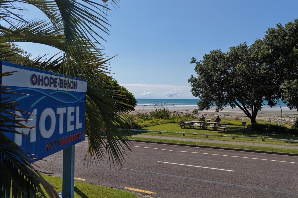 a sign on the side of a road next to a beach at Ohope Beach Motel in Ohope Beach