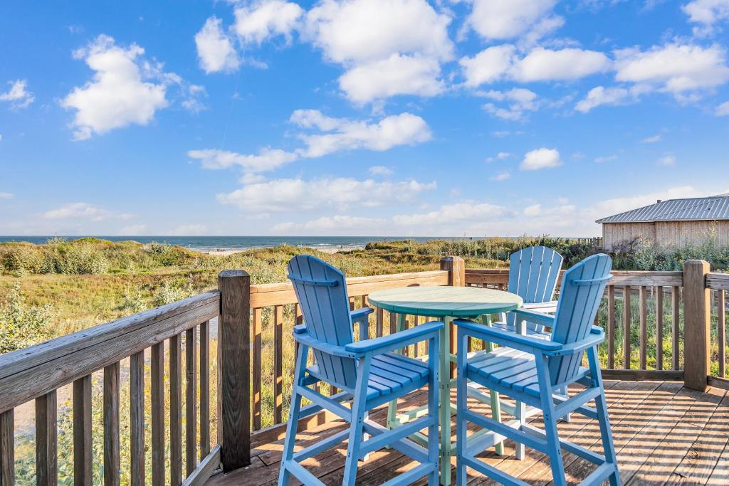 a table and chairs on a deck with a view of the ocean at Crandalls Cottage in Port Aransas