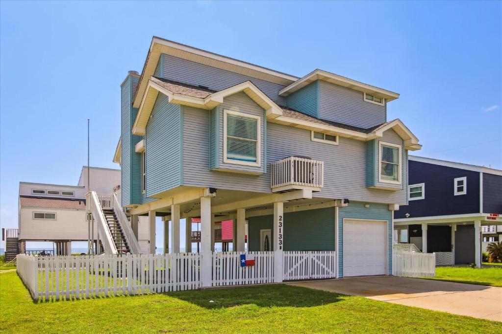 a house with a white fence in front of it at Pelican Path in Galveston