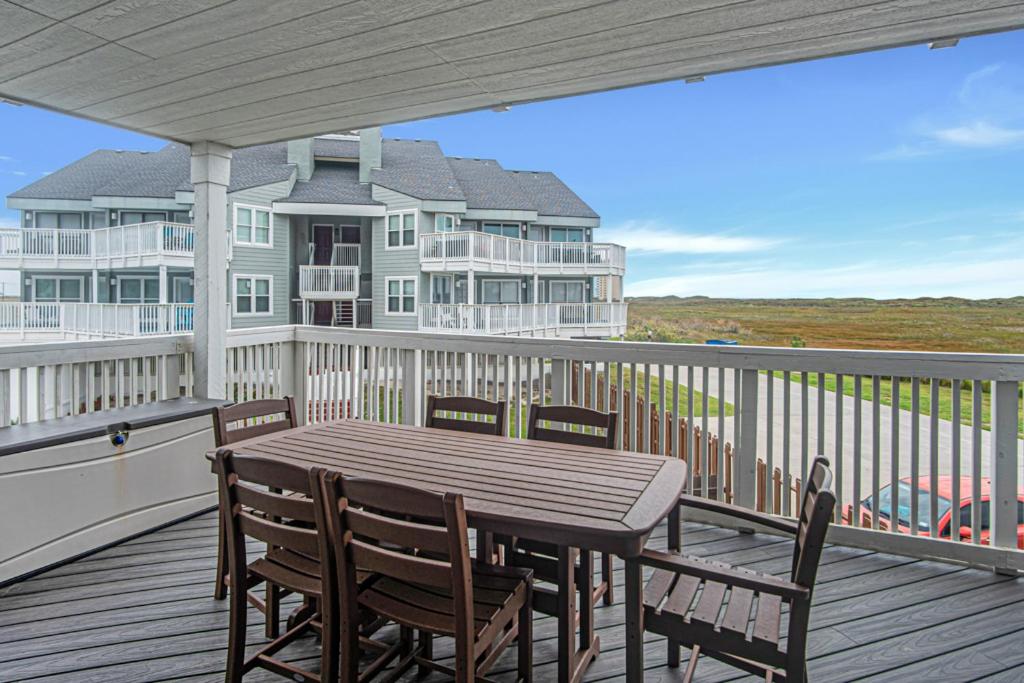 a deck with a table and chairs and a house at Pawsitively Paradise in Mustang Beach