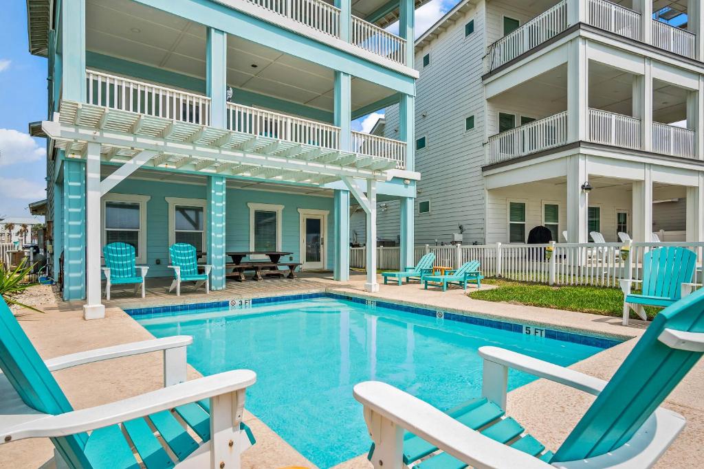 a swimming pool with blue chairs and a house at Beach-A-Holic in Padre Island