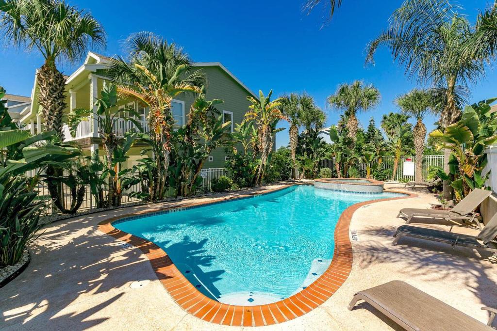 a swimming pool in front of a house with palm trees at 3 Sheets To the Zin in Port Aransas