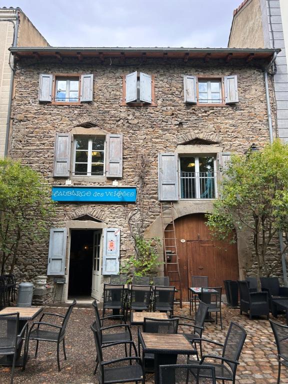 a brick building with tables and chairs in front of it at Auberge des Veillees in Blesle