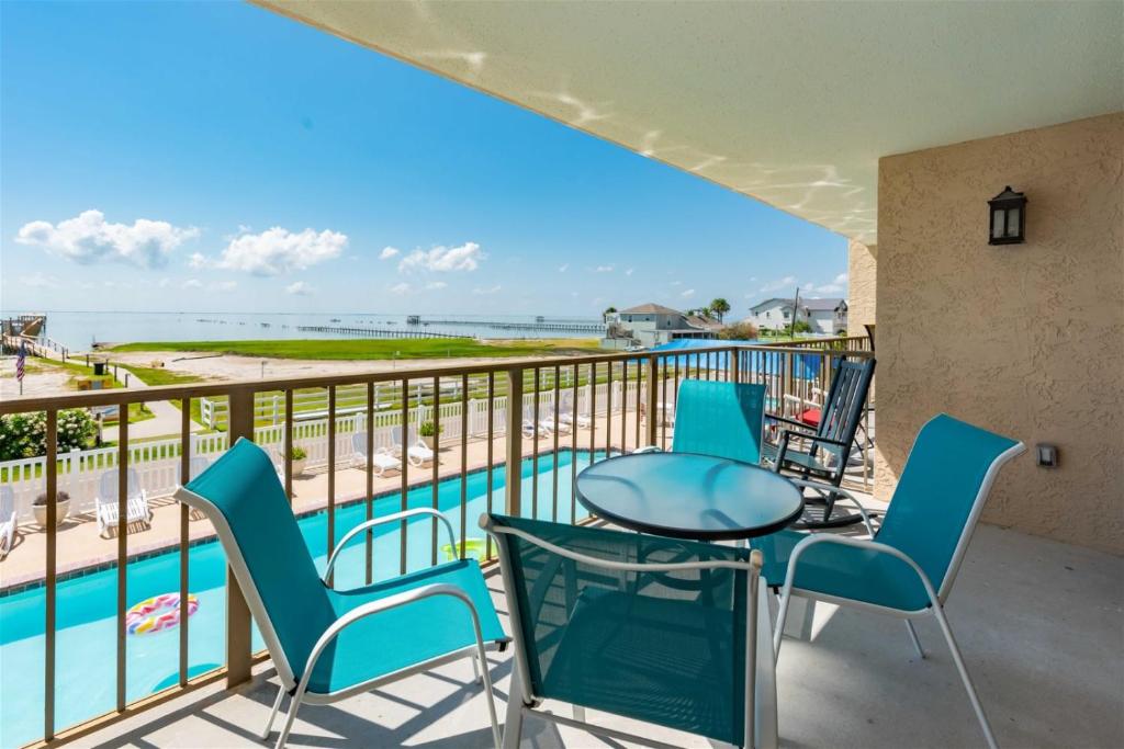 a balcony with a table and chairs and a view of the beach at Laguna Reef #208 - Sea Happiness in Rockport