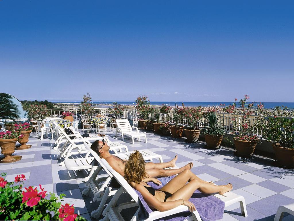 two women laying on lounge chairs on the beach at Hotel Miramare in Bibione