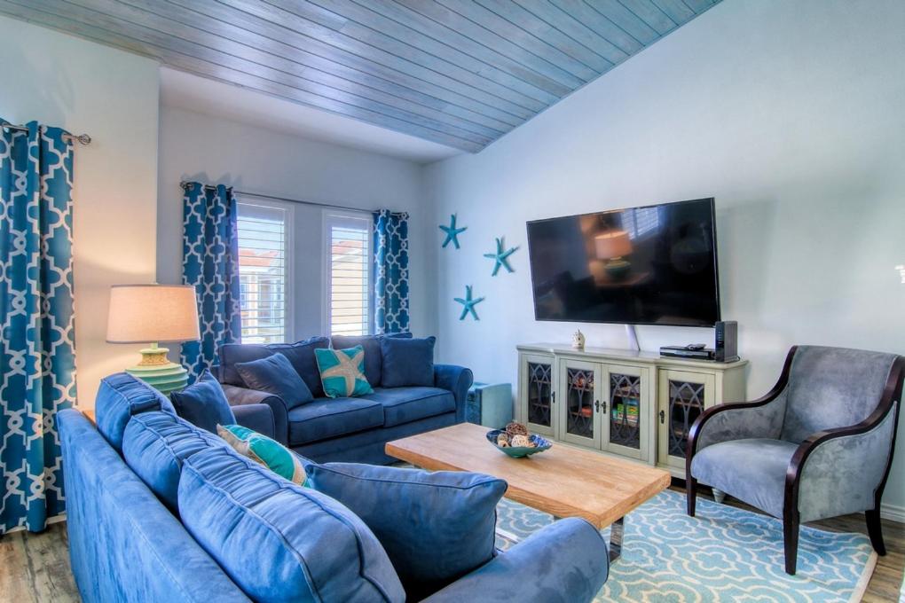 a living room with blue furniture and a flat screen tv at Flip Flops & Pop Tops in Port Aransas