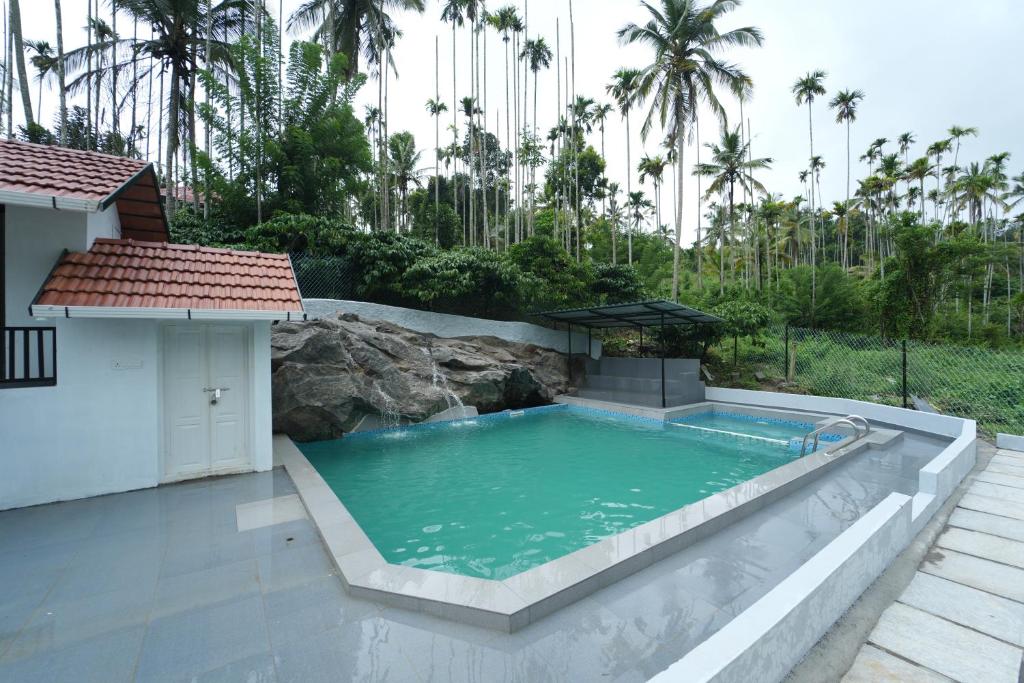 a swimming pool with a waterfall in a backyard at Wayanad Palm Grove Retreat 1st Floor in Wayanad