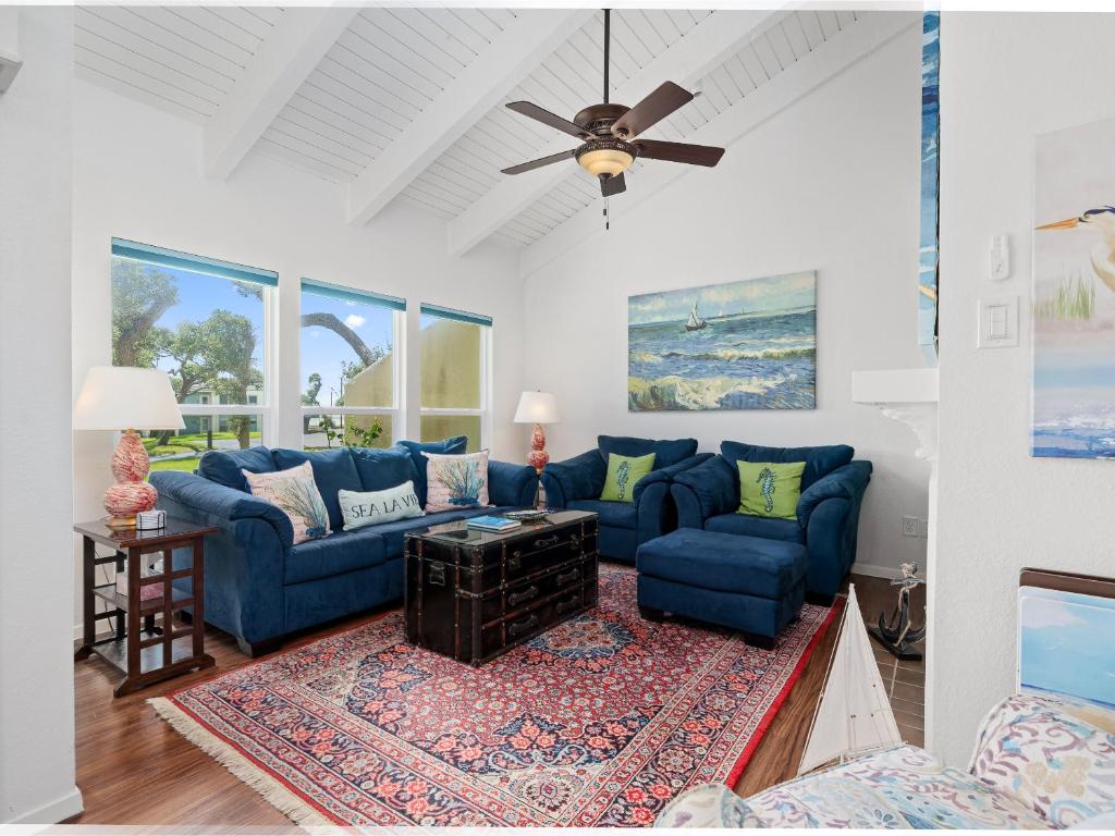 a living room with blue couches and a ceiling fan at Beautiful Bay View Condo in Rockport