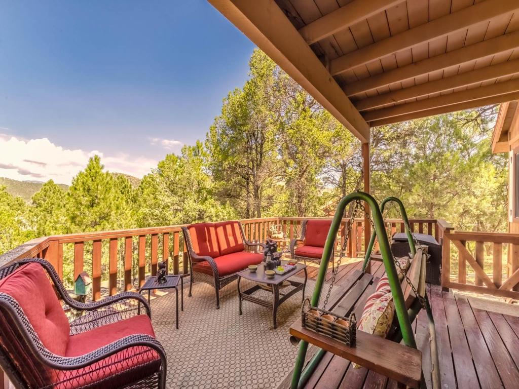 a deck with chairs and a table and chairs at Mockingbird Cabin in Ruidoso