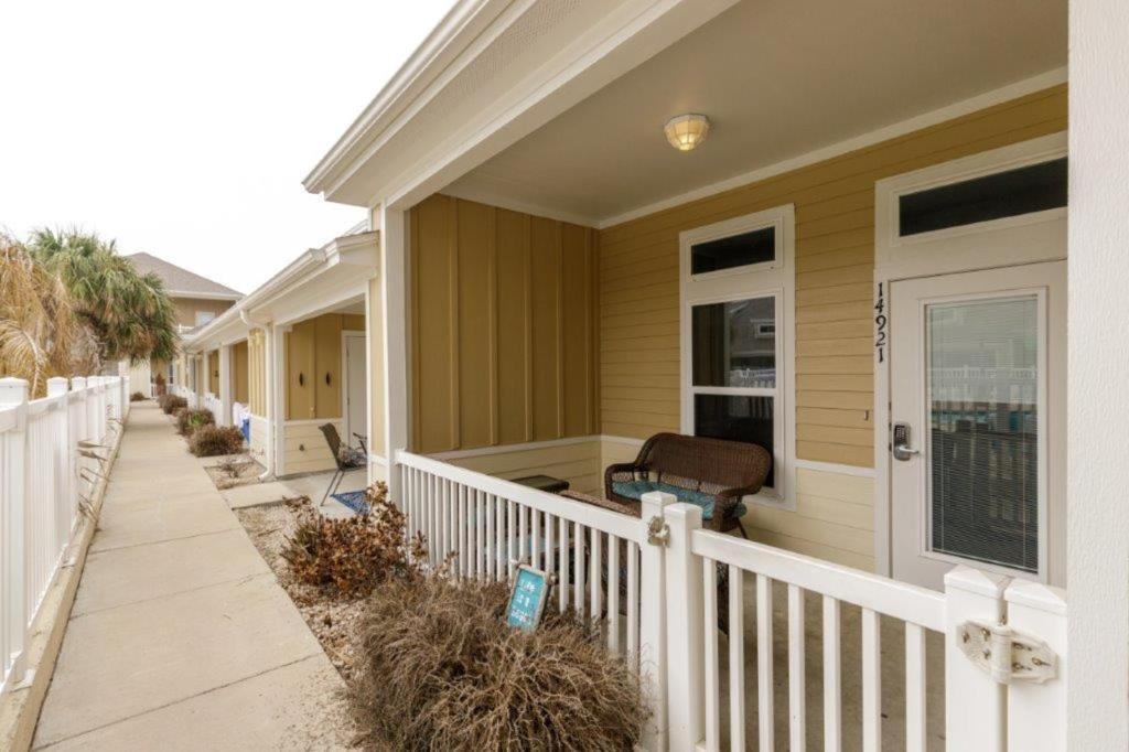 a house with a white fence and a porch at Lets Padre at Village by the Beach in Padre Island