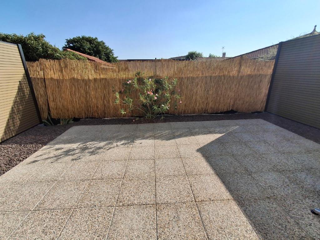 a backyard with a wooden fence and a sidewalk at Studios Saint Mau 3 in Saint-Maurice-de-Gourdans