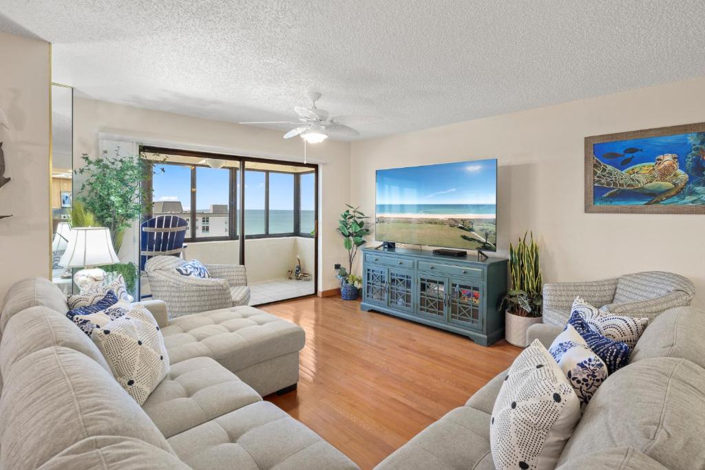 a living room with two couches and a television at Oceanfront Penthouse 11b in Ormond Beach