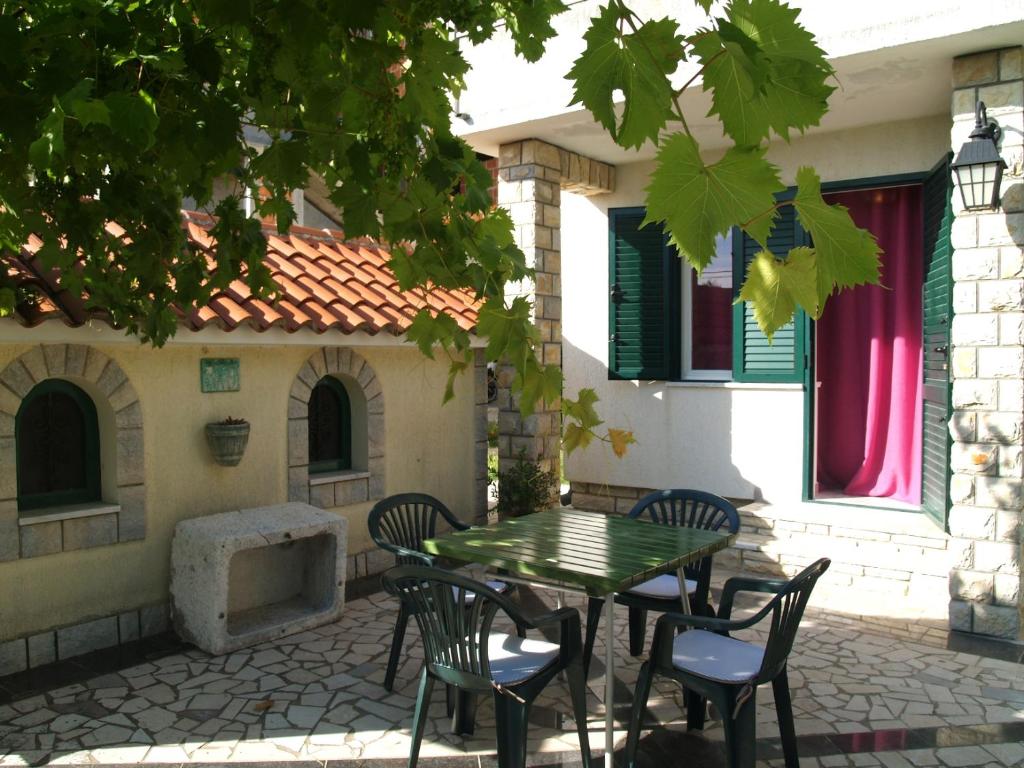 a patio with a table and chairs in front of a house at Apartment Roglić in Rab