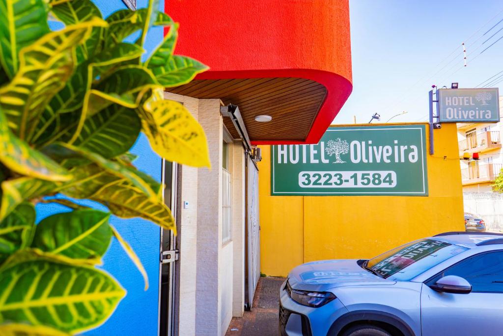 a car parked in front of a building with a sign at Hotel Oliveira in Goiânia