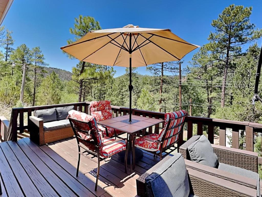a table and chairs on a deck with an umbrella at Knotty Pines Cabin in Ruidoso