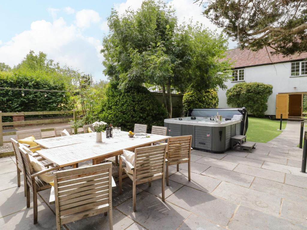 a patio with a table and chairs and a grill at Lower Tundridge Cottage in Suckley