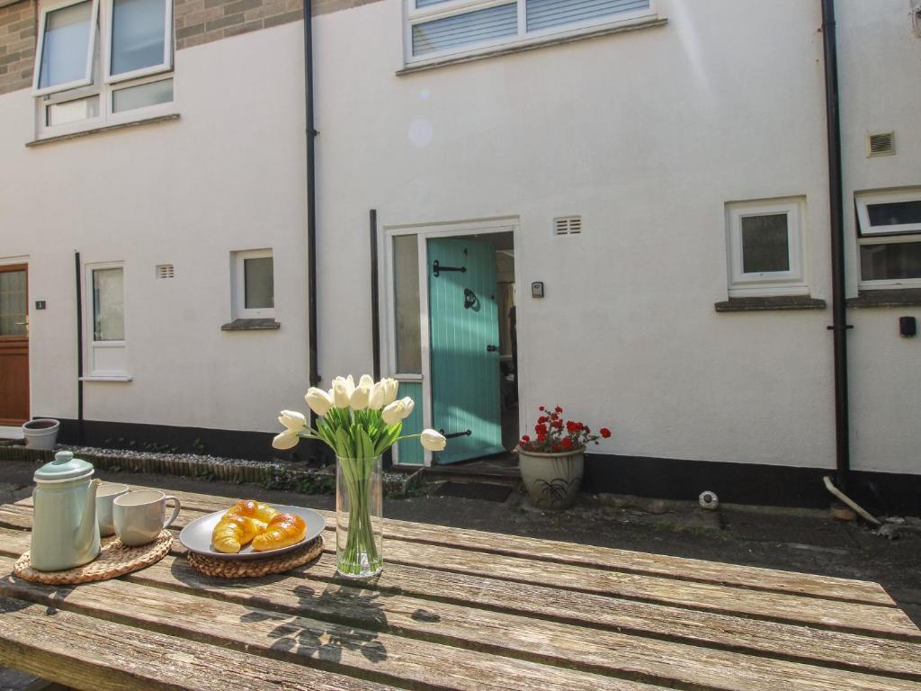 a table with a vase of flowers and oranges on it at 4 Thornlea Mews in Kingsbridge