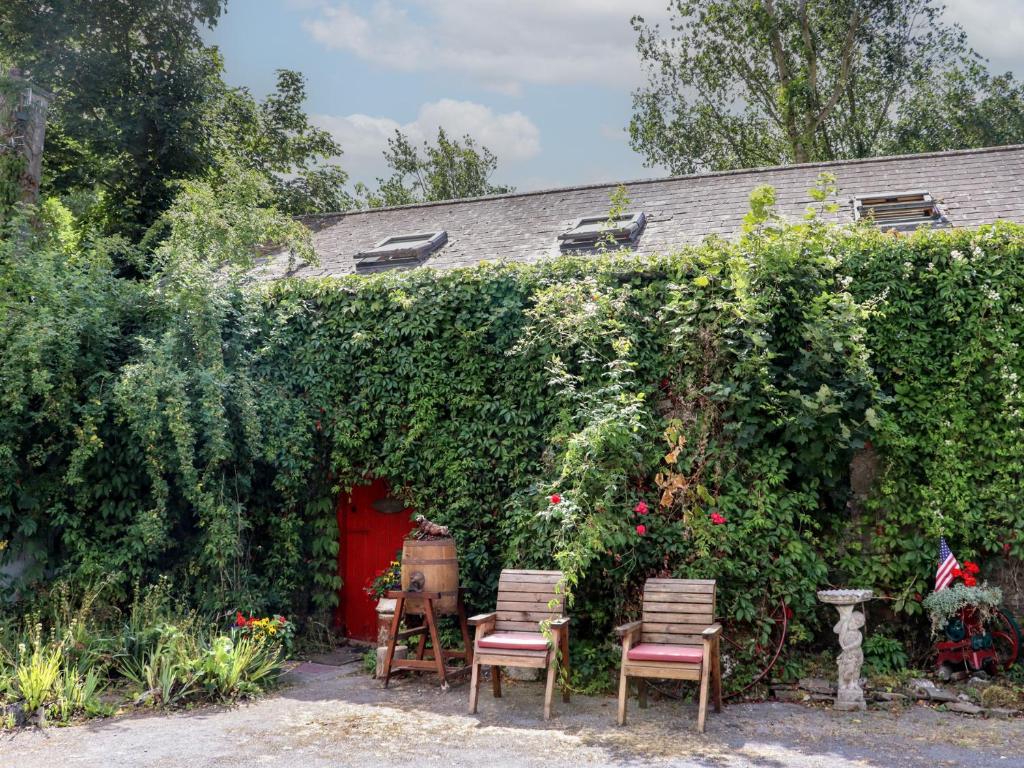 a hedge with chairs and a red door at Ryan's Loft in Ardfinnan