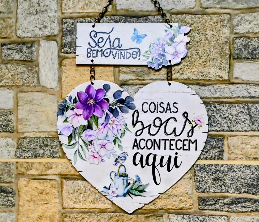 a sign on a brick wall with flowers on it at Refúgio Alemar in Ribeirão Preto