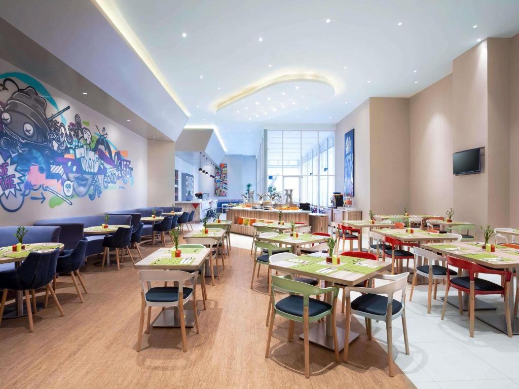 a restaurant with tables and chairs and a mural at Ibis Styles Jakarta Mangga Dua Square in Jakarta