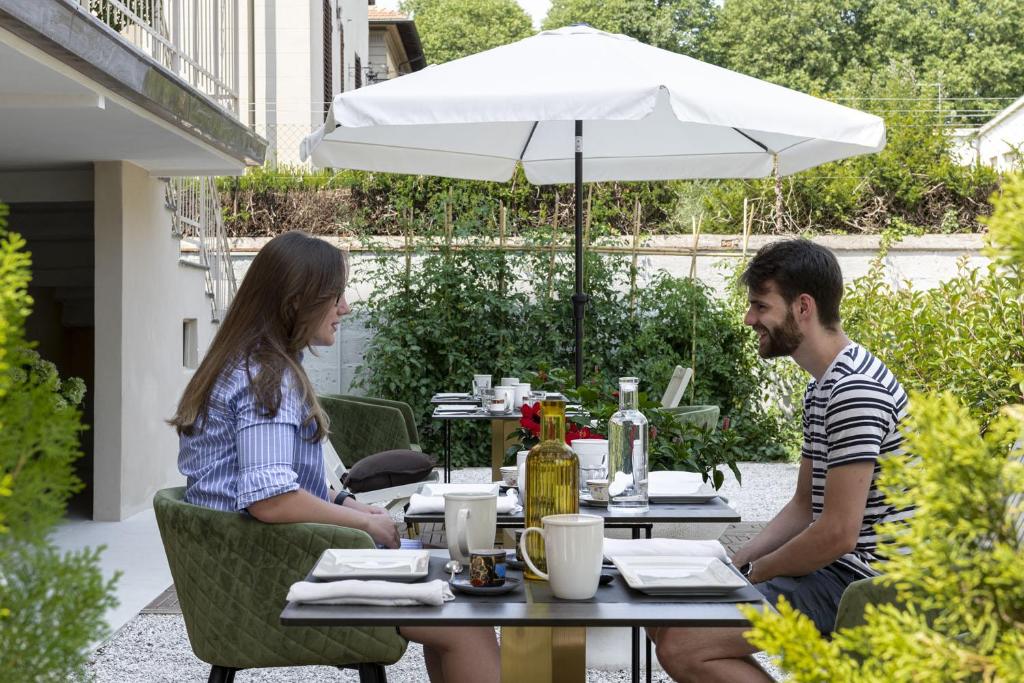 a man and woman sitting at a table under an umbrella at Villa La Tuia B&B in Lucca