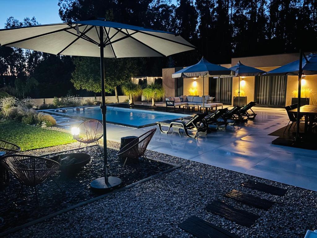 a swimming pool with umbrellas and tables and chairs at Casa D'avó Amália in Travanca