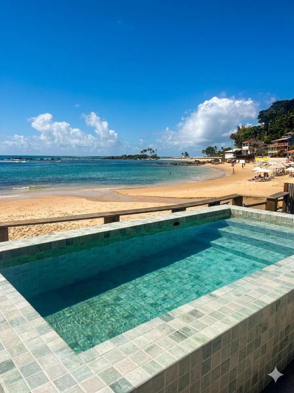 a swimming pool with a beach in the background at Pousada Morena in Morro de São Paulo