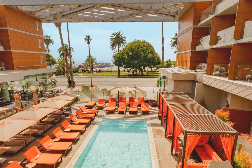 an outdoor swimming pool with orange lounge chairs and a hotel at Shore Hotel in Los Angeles